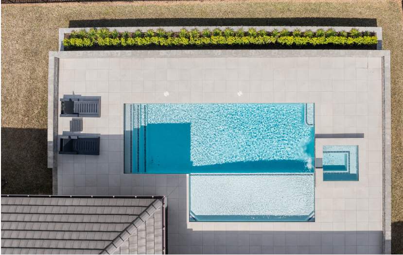 Aerial view of a pool surrounded by greenery and lounge chairs