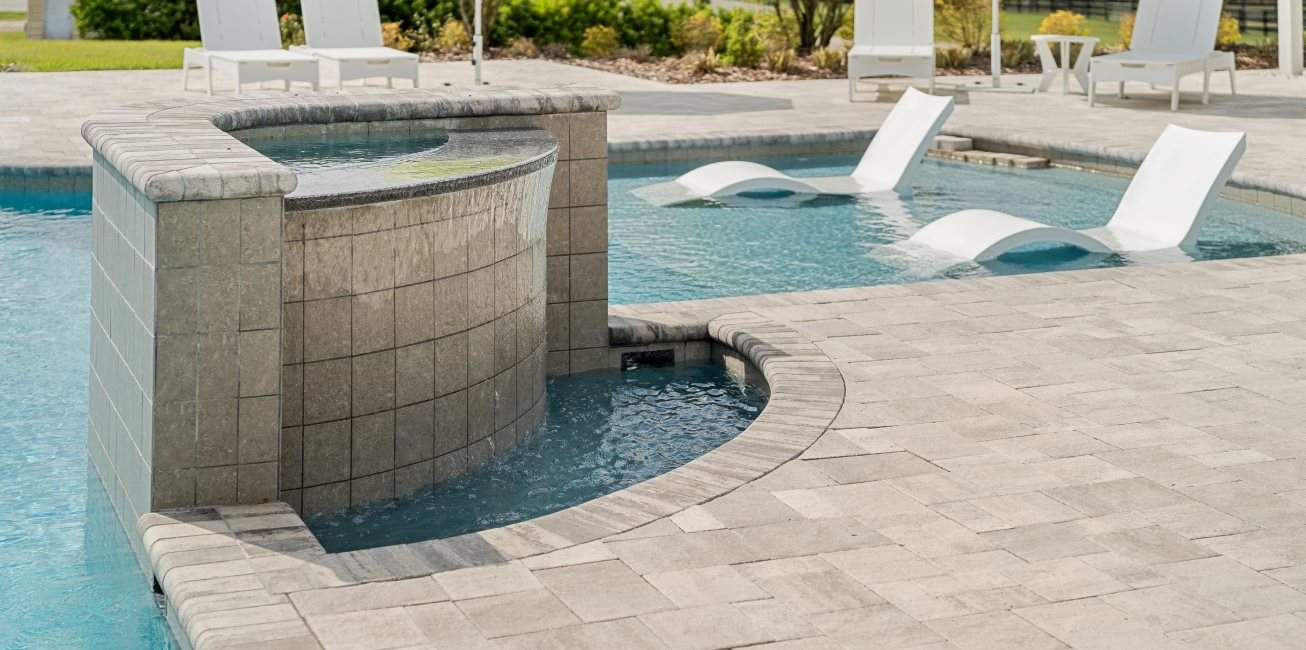 A pool area with a grotto feature and lounge chairs