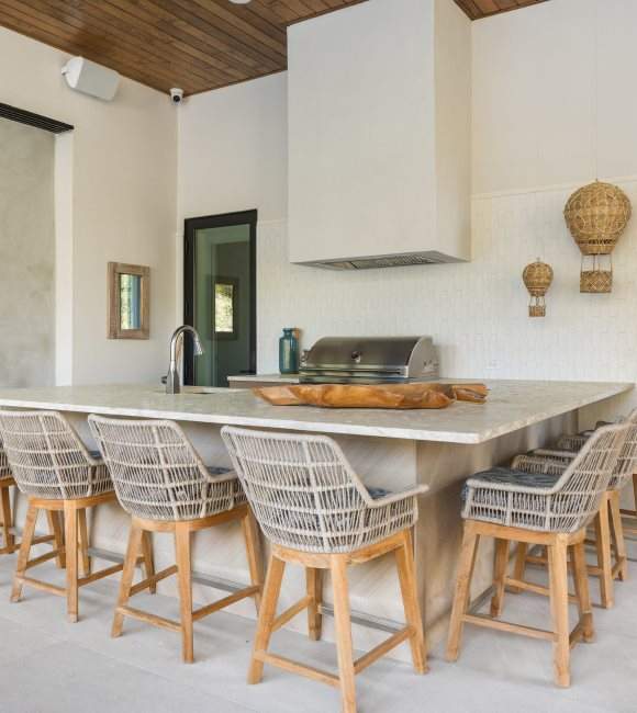 Outdoor kitchen featuring a island surrounded by several chairs
