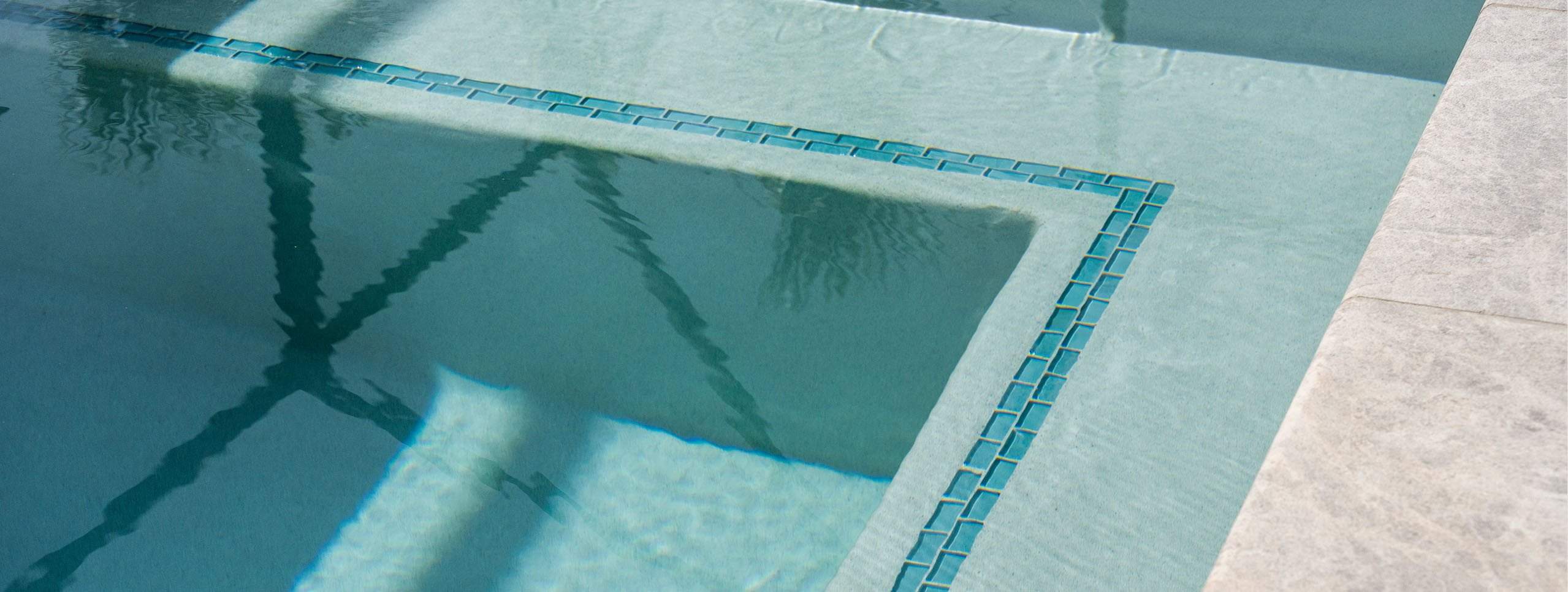 A corner of a pool with a ledge