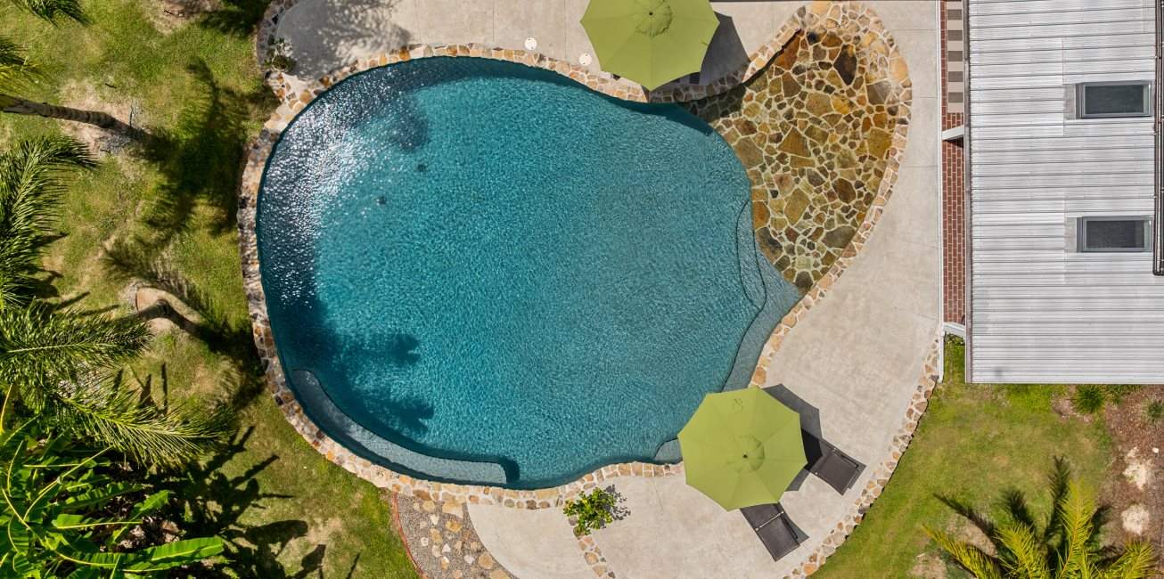 Aerial view of a swimming pool surrounded by green landscaping