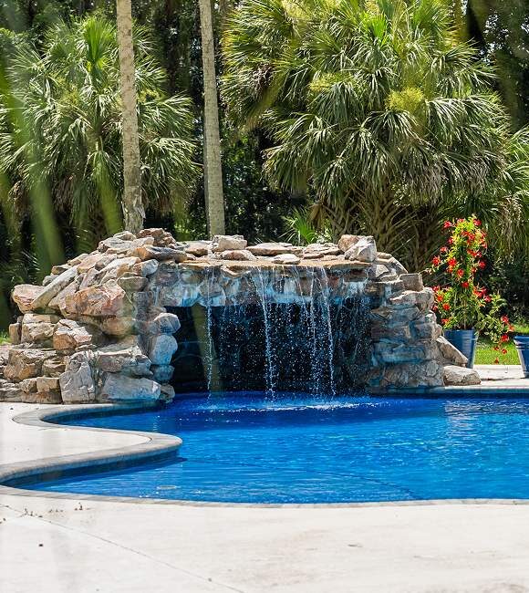 pool featuring a waterfall surrounded by tropical trees