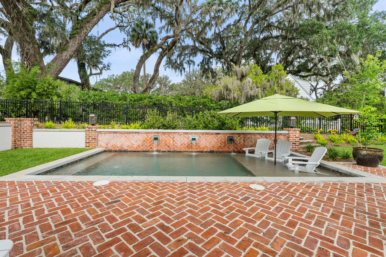 A brick patio featuring a swimming pool and a large umbrella